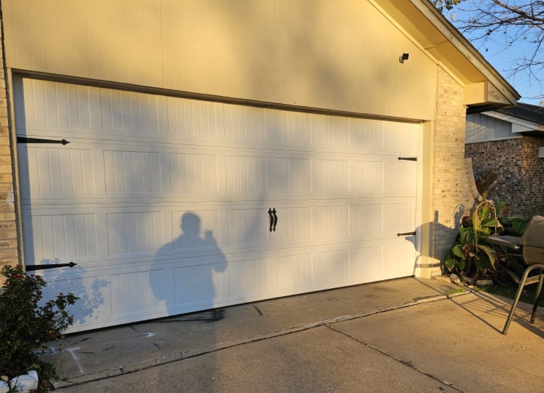 White 16x7 carriage-style garage door with black decorative hinges and handles