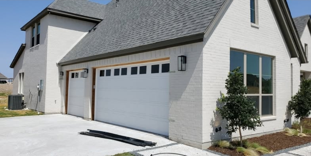 White garage doors with window inserts on a new white brick home in DFW