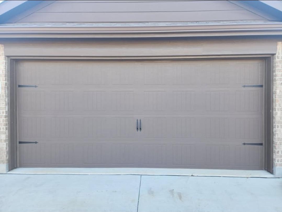Bronze long-panel garage door with black carriage-style hinges and handles