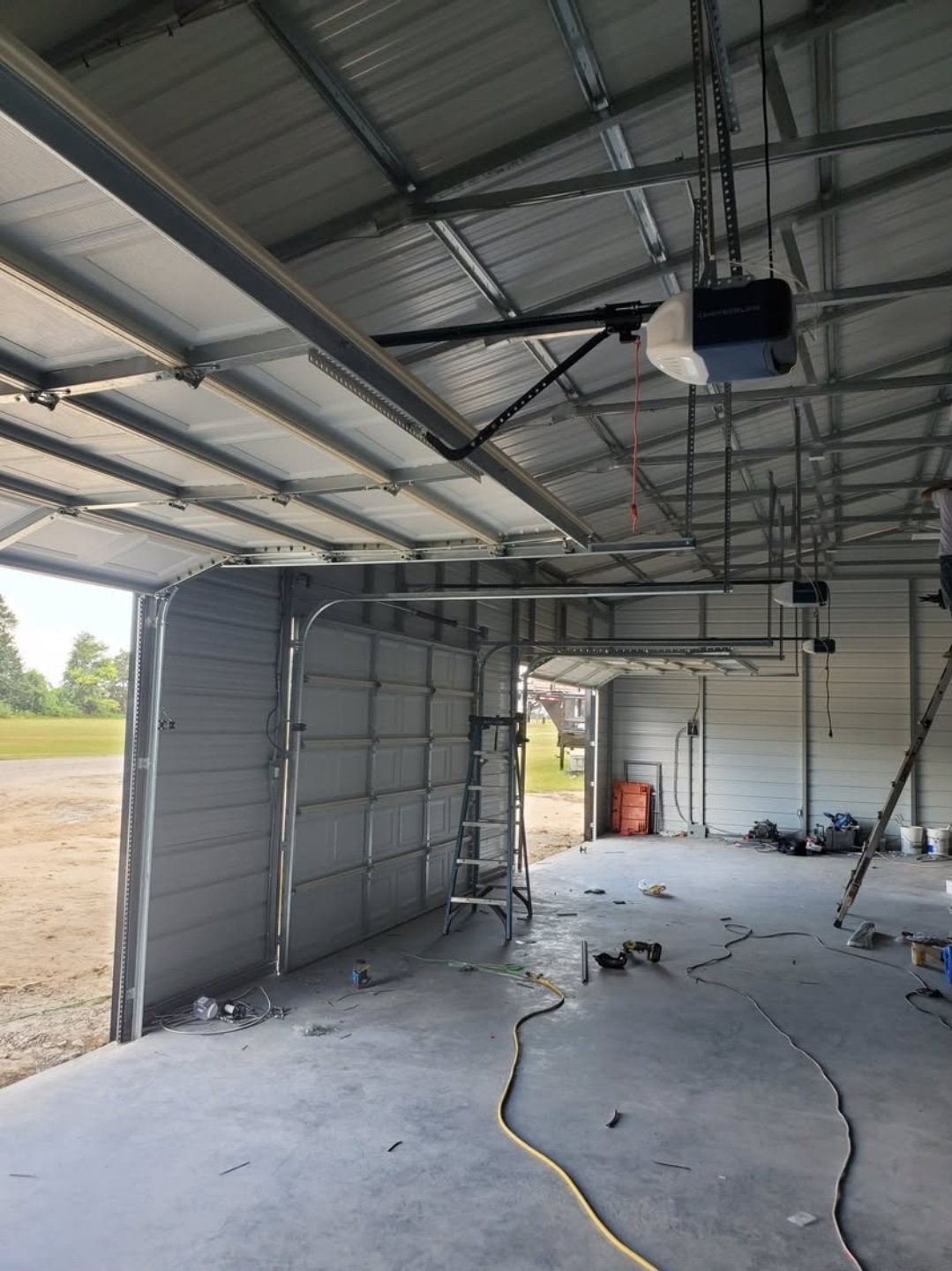 Garage doors and openers installed inside a large metal shop building